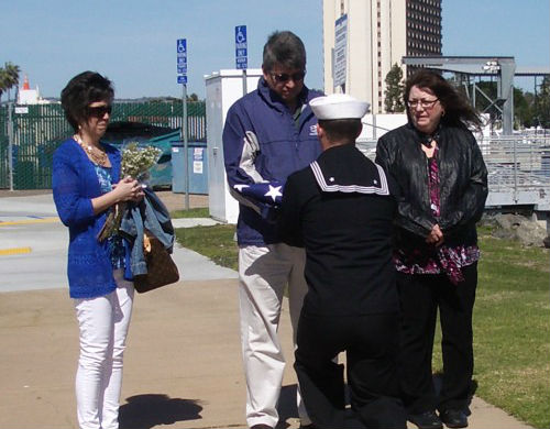 Sailor presenting flag to family